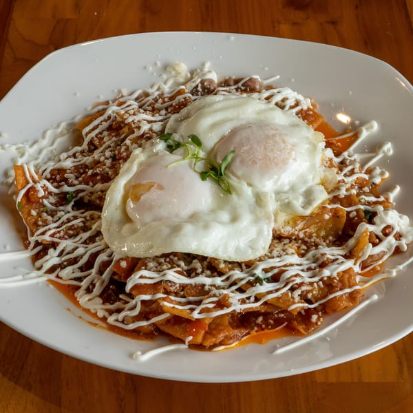 Mi Sabor Mexican Kitchen's chilaquiles with two fried eggs, drizzled with crema and sprinkled with cheese.
