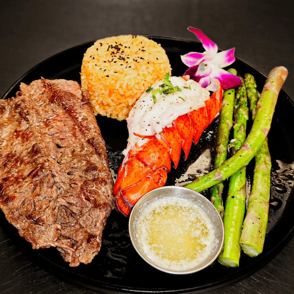 Mi Sabor Mexican Kitchen's surf and turf with steak, lobster tail, rice, asparagus, and butter.